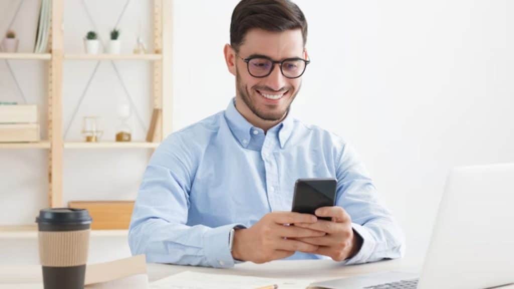 A man smiling while texting on his phone