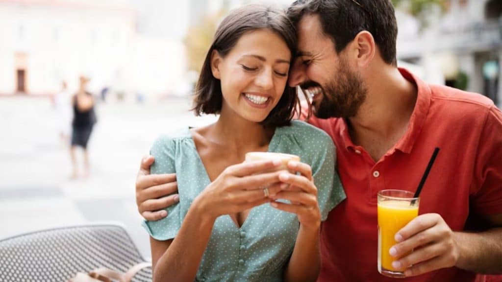 A man surprising his partner with her favorite drink