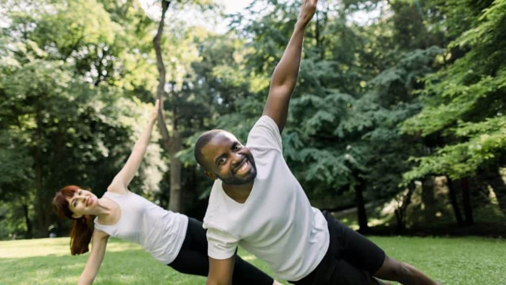 A couple doing yoga together in a park