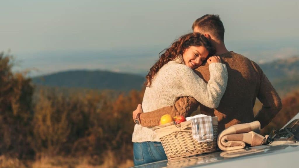 A couple holding each other while the sun sets