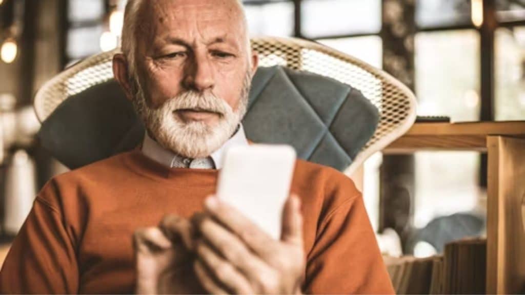 A man sitting alone on a couch looking at his phone