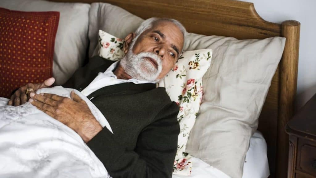A man lying awake in bed looking at the clock