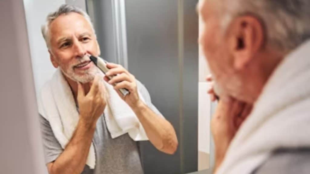 A man shaving in front of a bathroom mirror