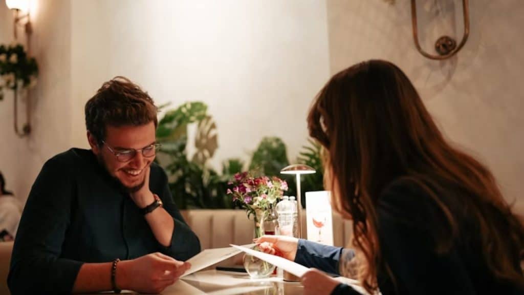 Cozy café with warm lighting and two people seated across from each other