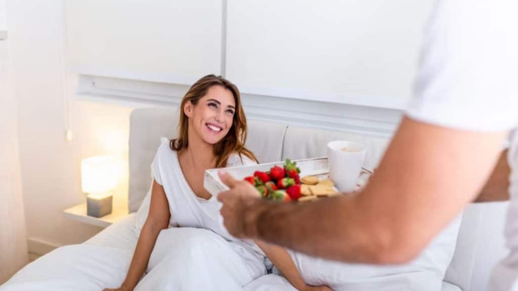A man surprising his partner with breakfast in bed