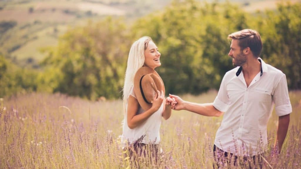 A couple walking hand in hand, smiling at each other