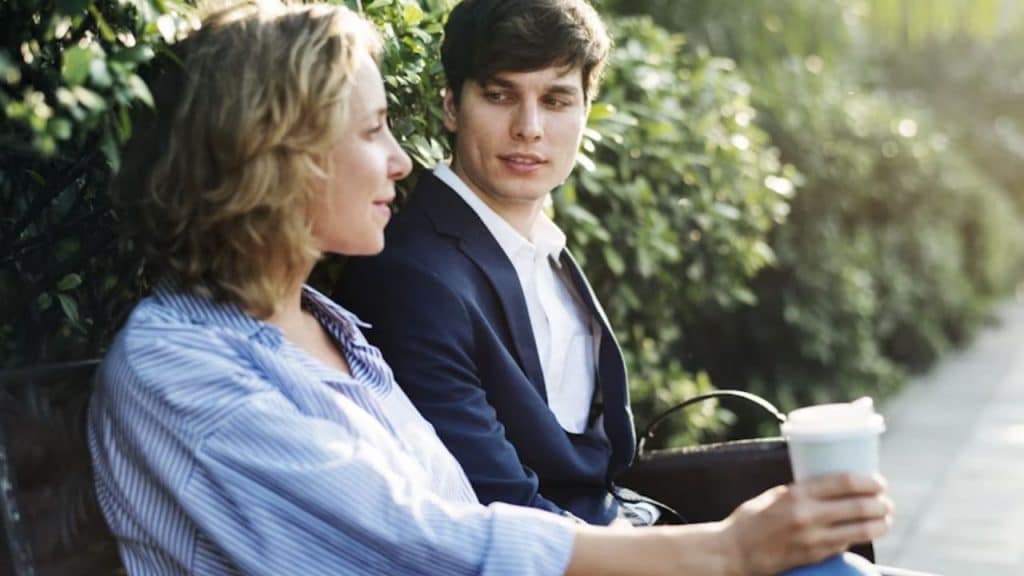 A man openly talking with his partner on a park bench