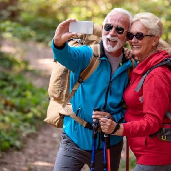 A happy couple taking selfie while hiking in the forest