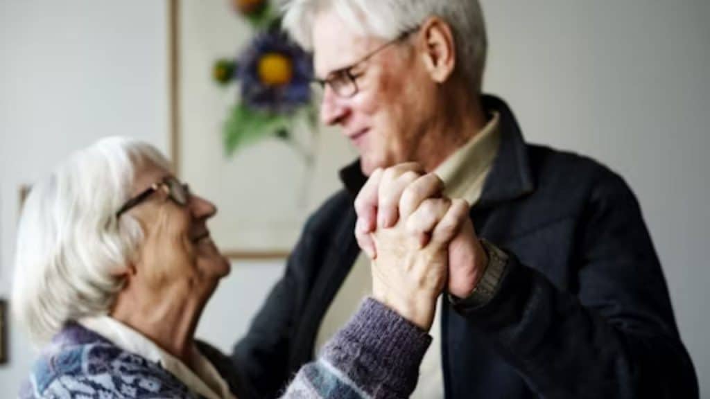 A couple holding hands while dancing and smiling warmly at each other.