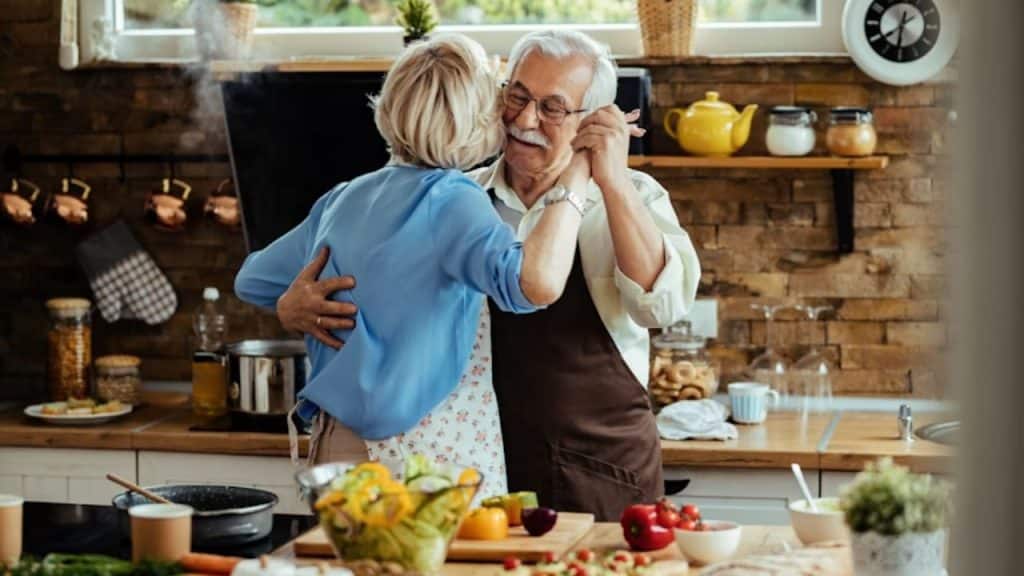 A couple hugging and dancing in the kitchen while cooking dinner