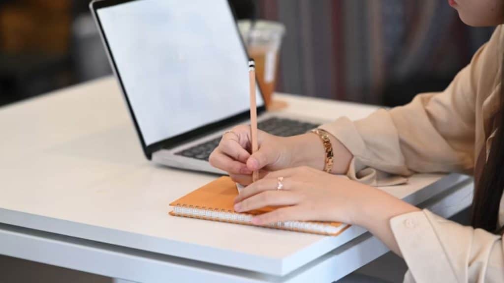 Woman writing in a gratitude journal at a desk