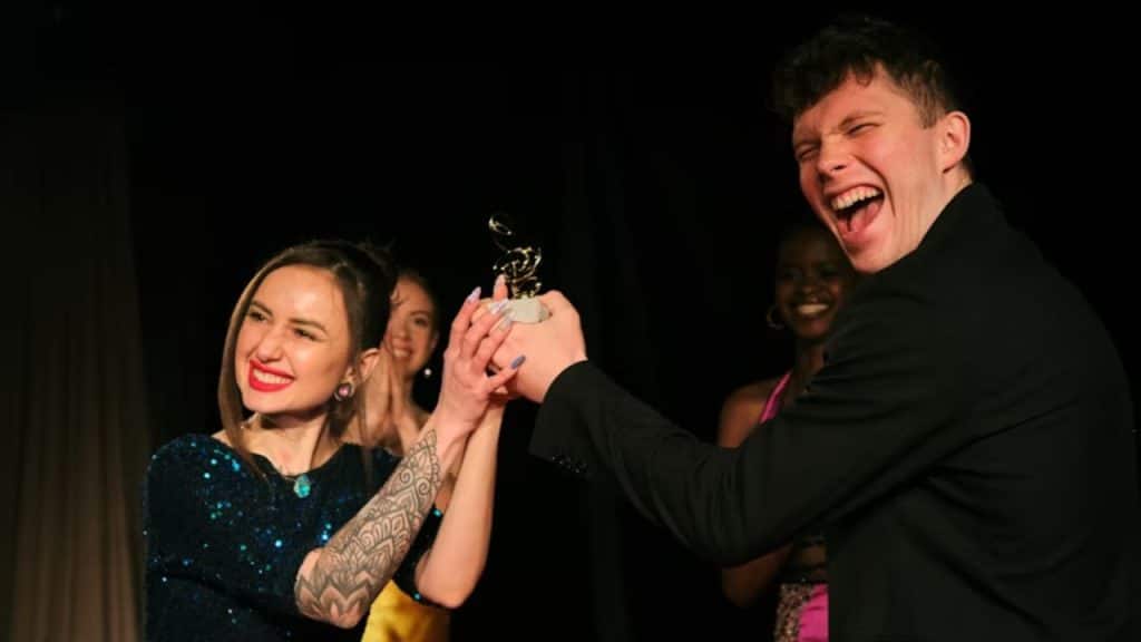 A woman cheering her partner after he receives an award.