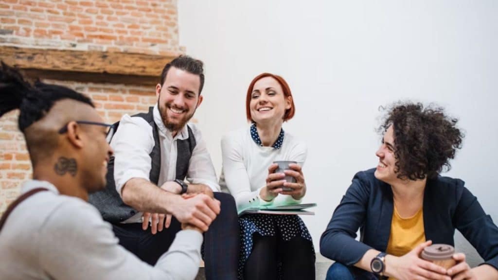 Man smiling with friends while partner chats nearby