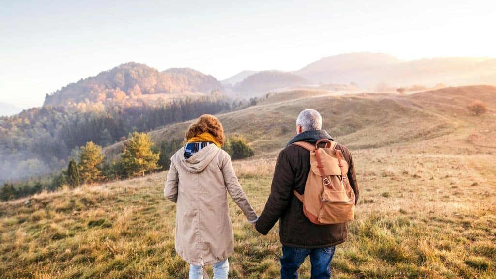A couple holding hands while hiking in the mountains at sunrise.