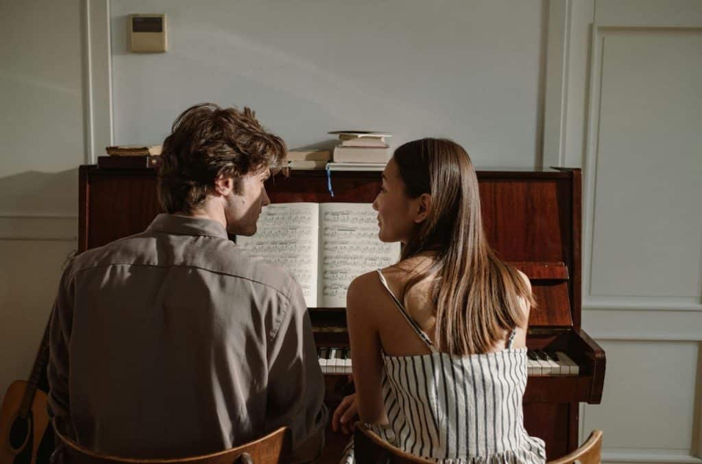 A man and woman in front of a piano