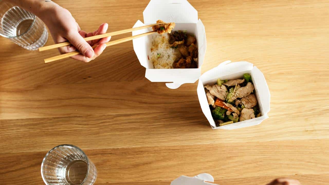 A top view of people eating takeout with chopsticks.