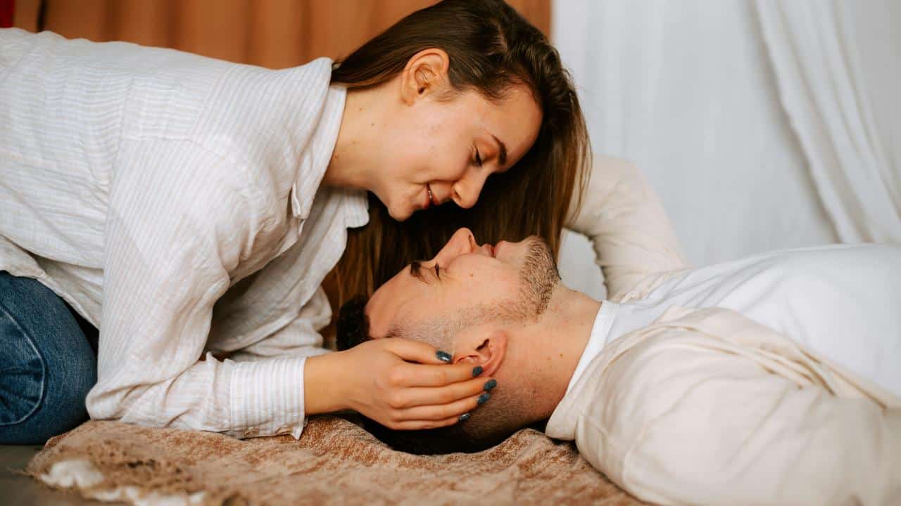 A woman leaning over a man lying on the floor, holding his head gently.