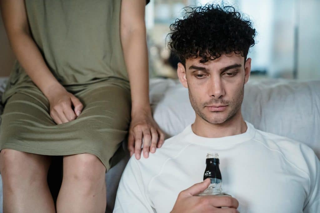 A man staring a nowhere and holding a bottle