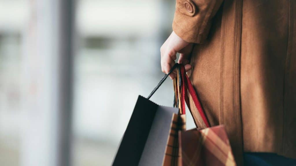 A person holding several shopping bags in one hand.