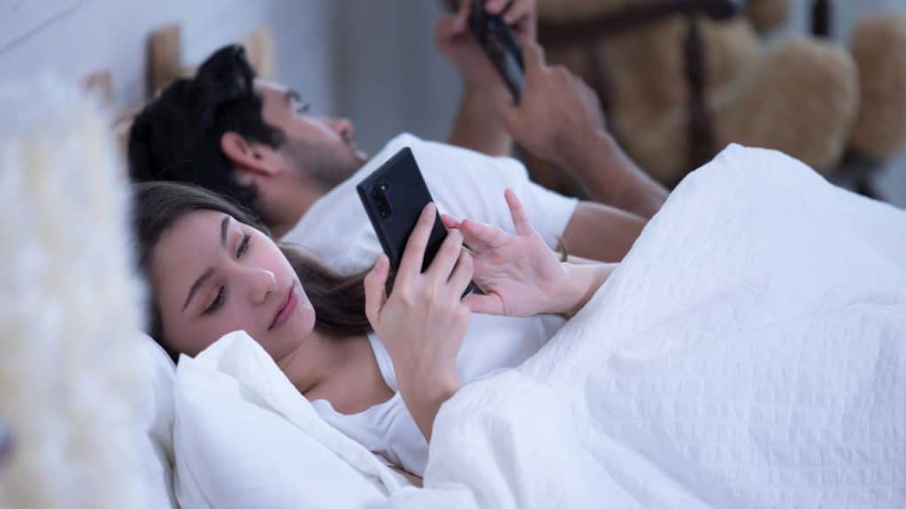 A couple lying in bed using their smartphones.