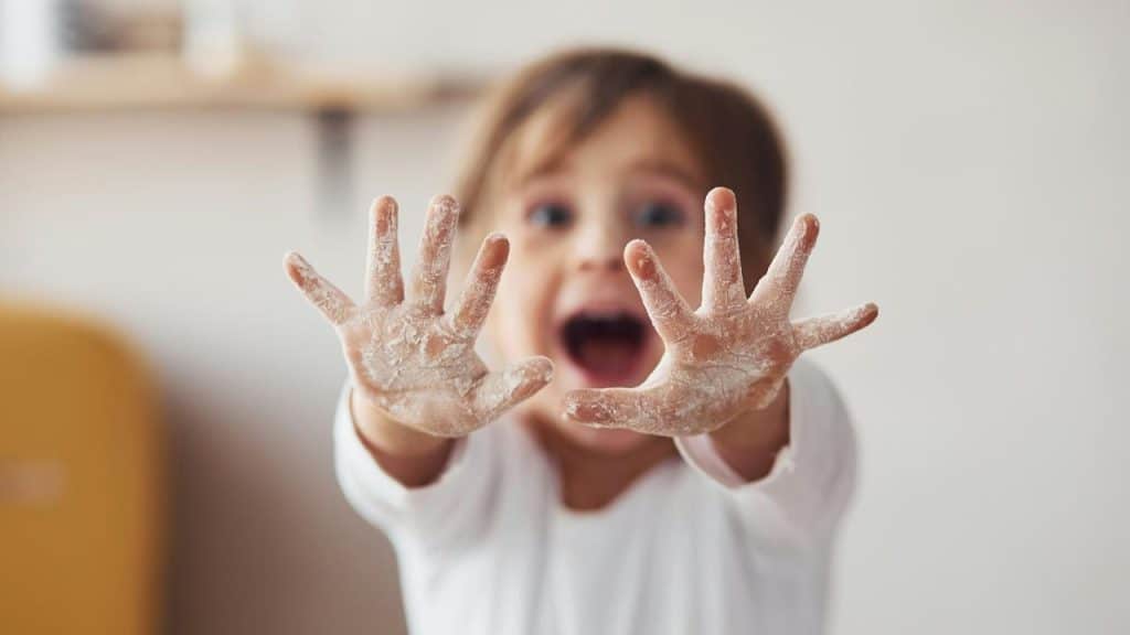 A child showing flour-covered hands with excitement.