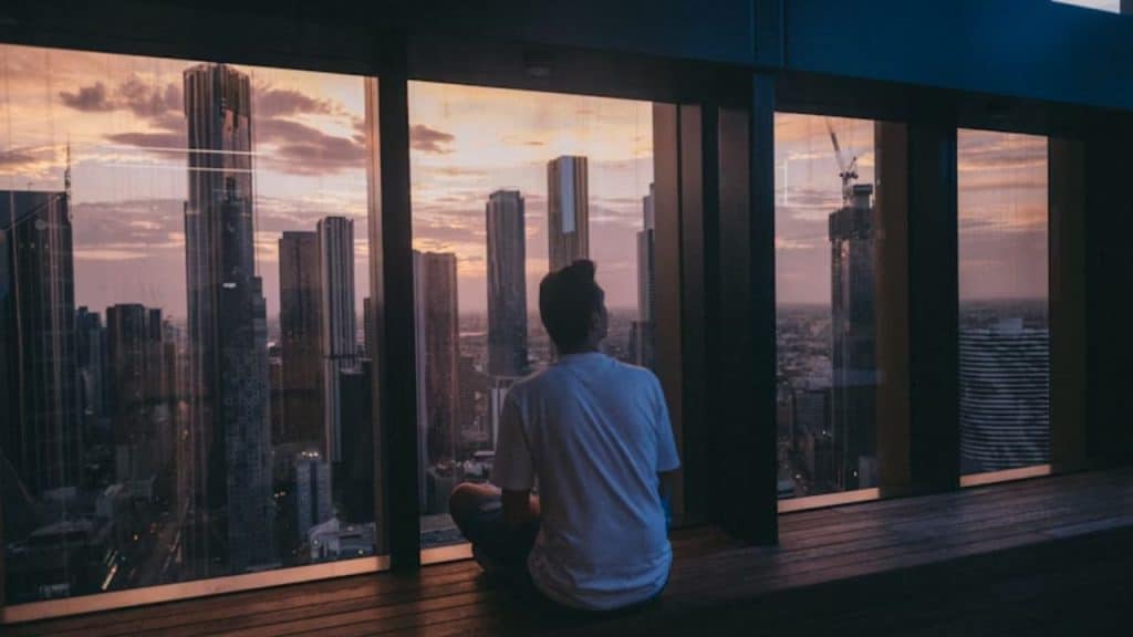 Man meditating on a balcony overlooking a city