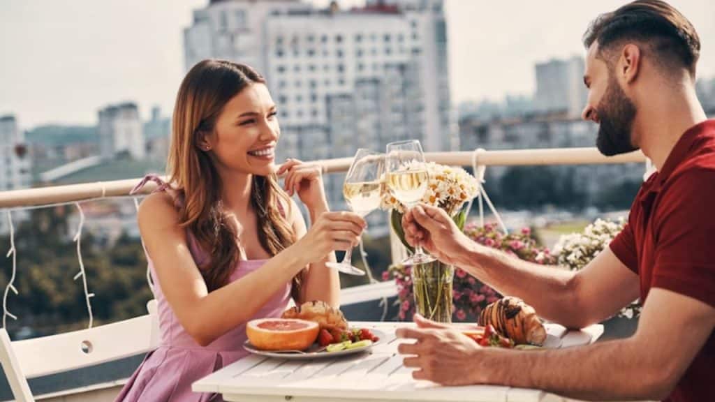 Couple smiling while enjoying coffee outdoors.