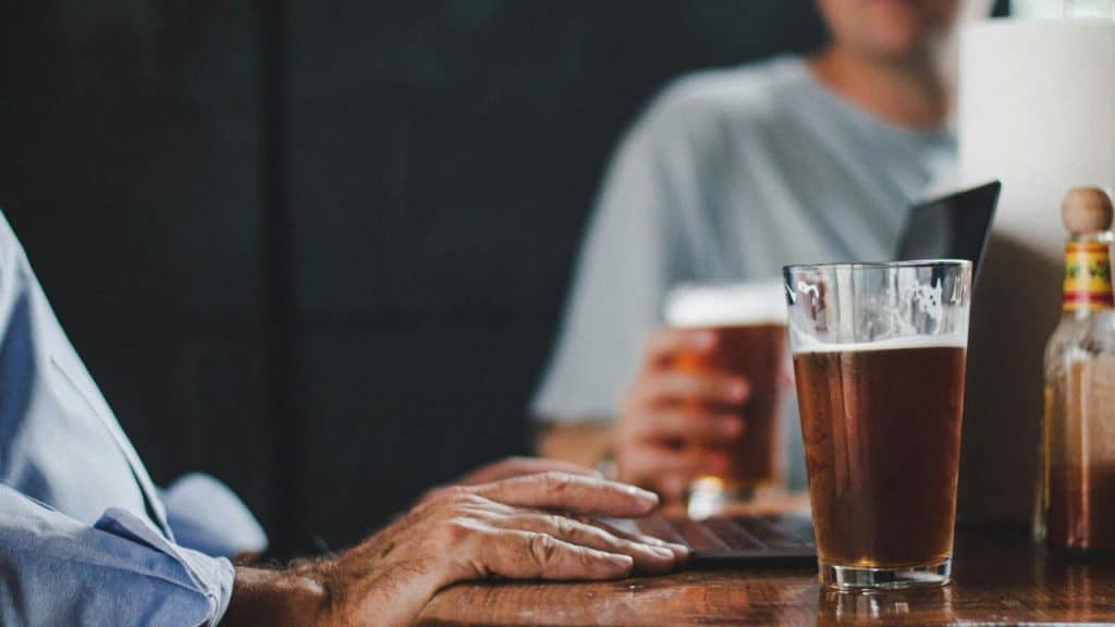 A close-up of two men sitting at a table with glasses of beer.
