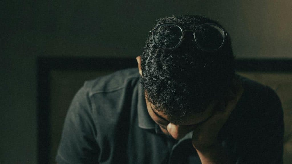 A man with glasses on his head sitting with his face resting on his hand.