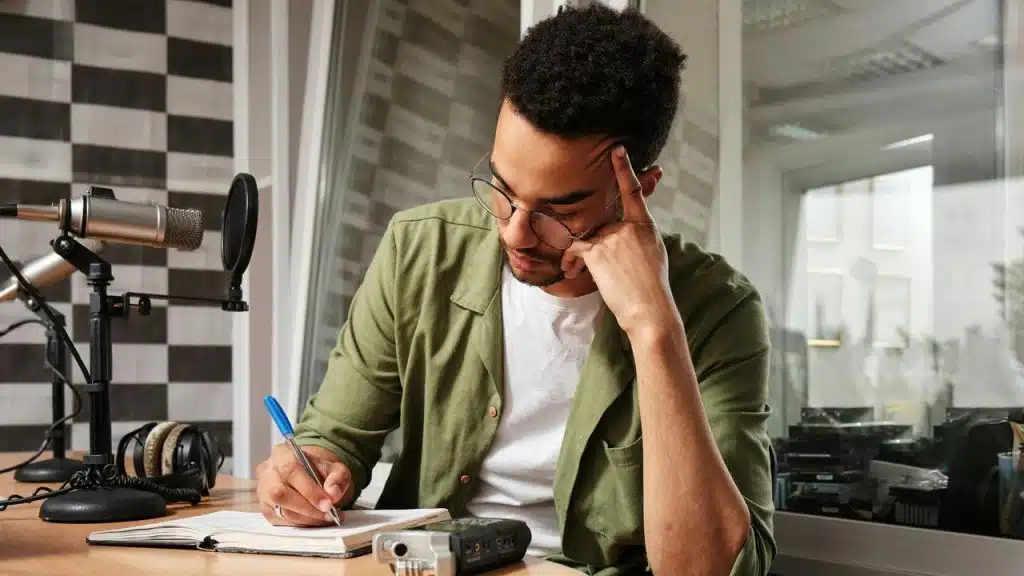 A man writing in a notebook in a recording studio.