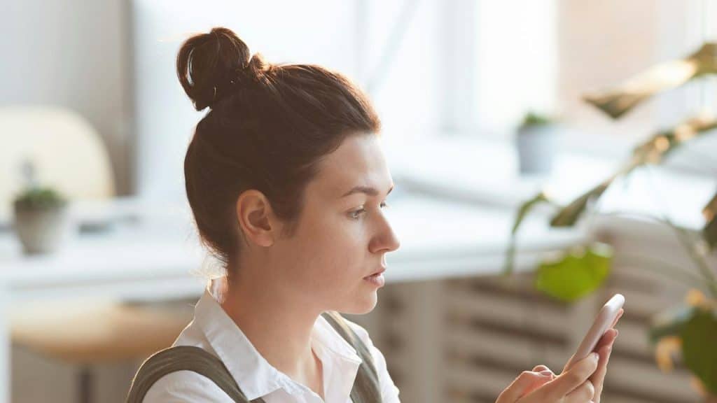 A woman looking at her phone in a bright room.