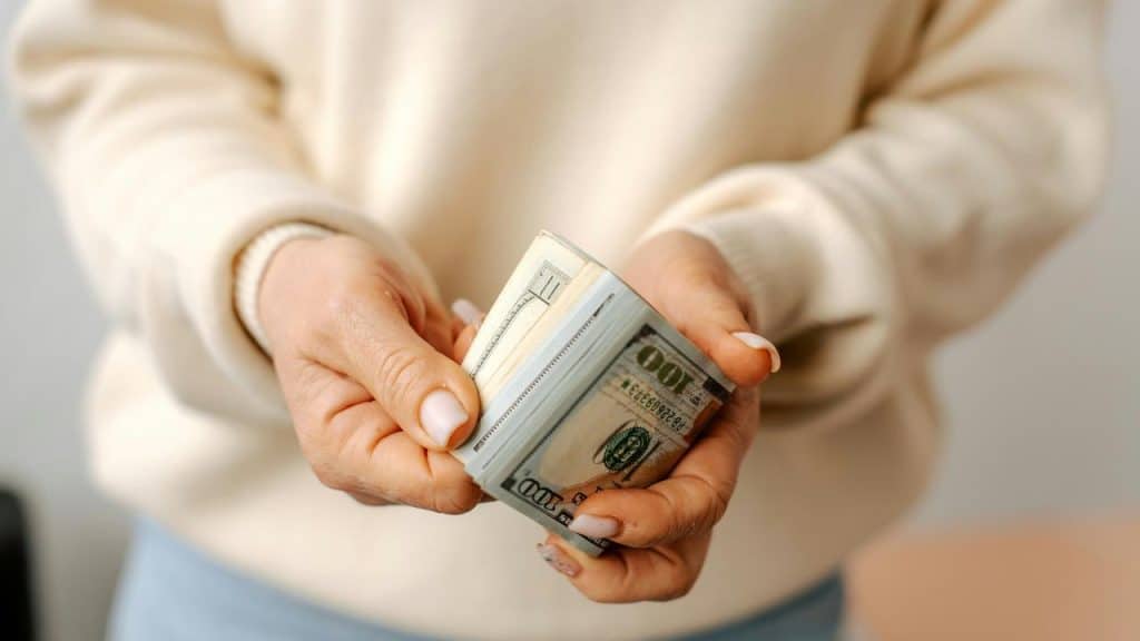 A person holding a stack of US dollar bills.