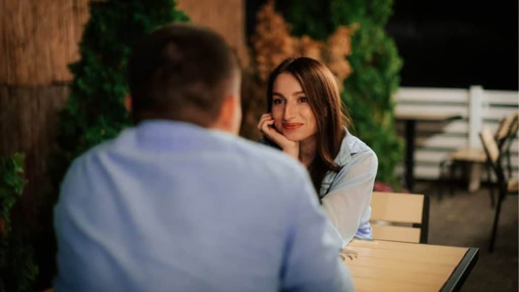 Man sitting confidently with a woman observing him silently