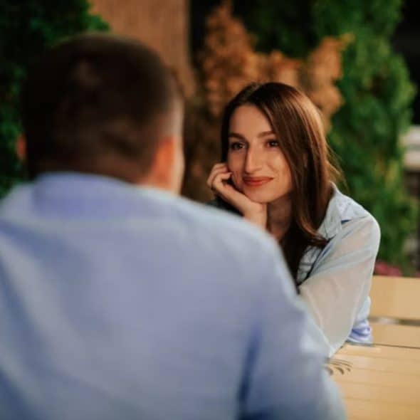 Man sitting confidently with a woman observing him silently