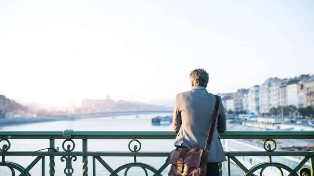 Man taking a deep breath while standing on a bridge view