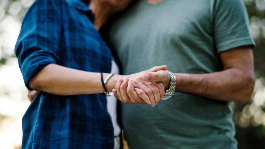 A couple holding hands closely outdoors.