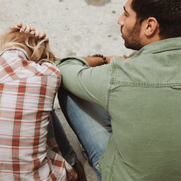 A couple sitting on a sidewalk