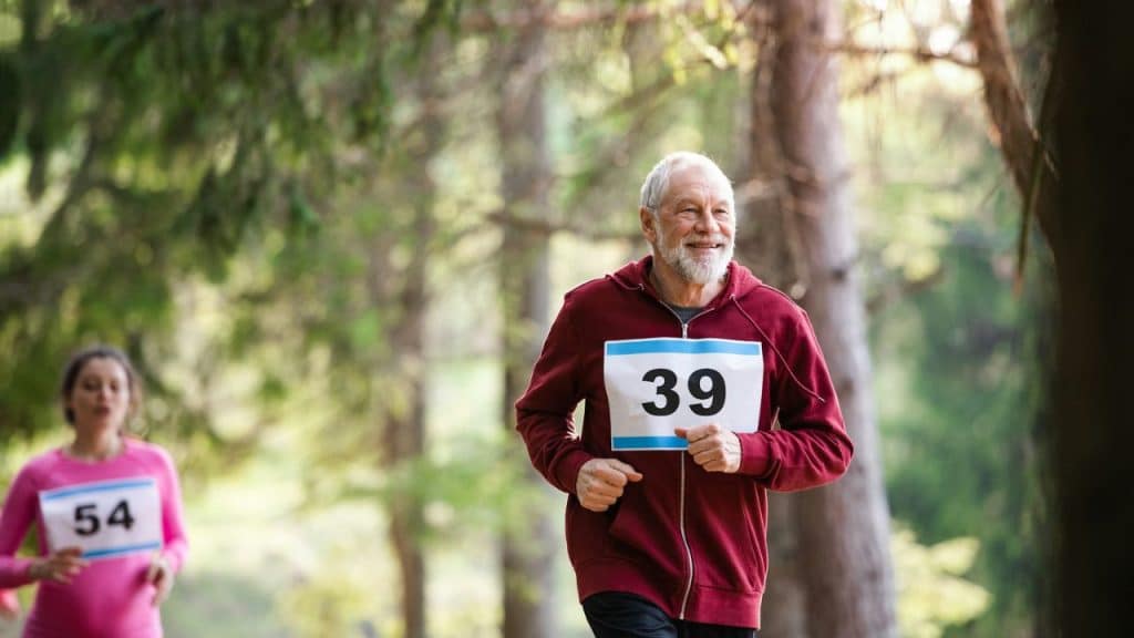 A happy, elderly man with a white beard is running in a race.