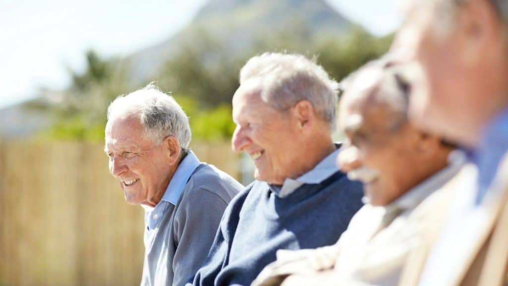 A group of older men sitting together, laughing and smiling.