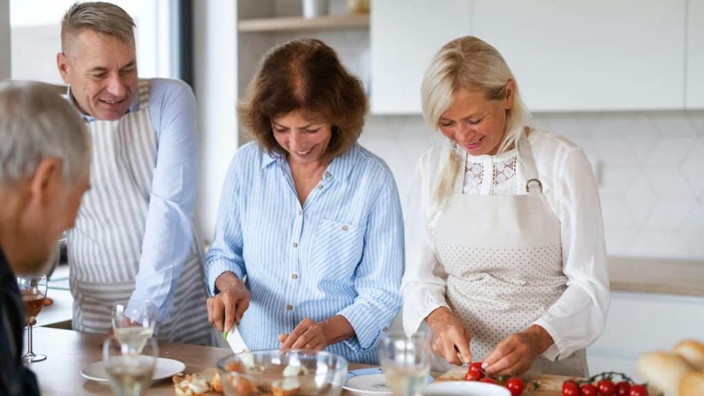 A group of older adults cooking together in a kitchen.