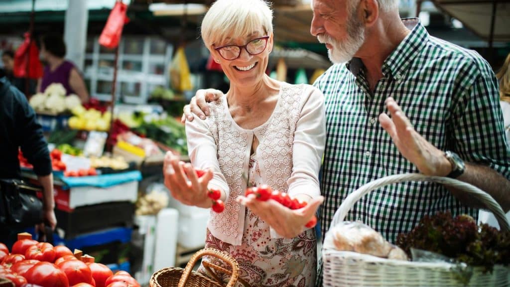 An older couple shopping for fresh produce at a market.