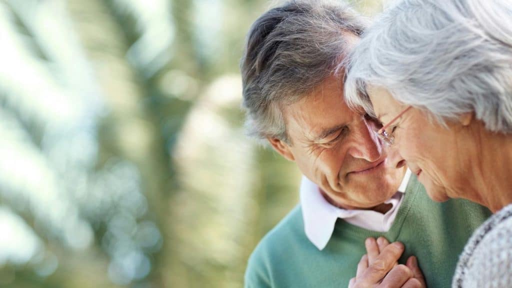 An older couple embracing with their foreheads touching.