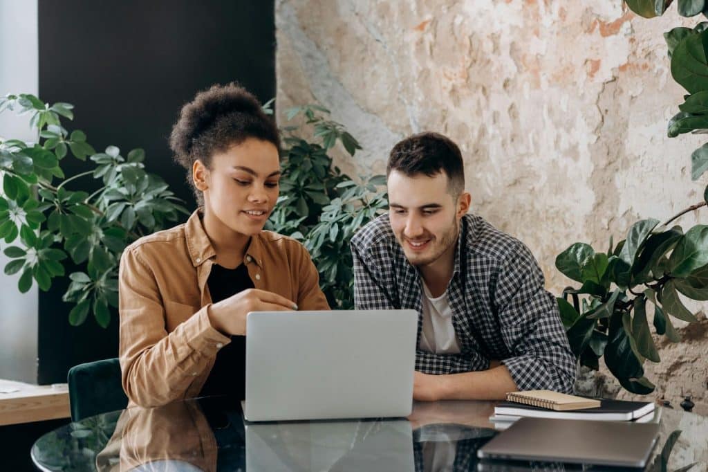 A man showing something from laptop to a woman
