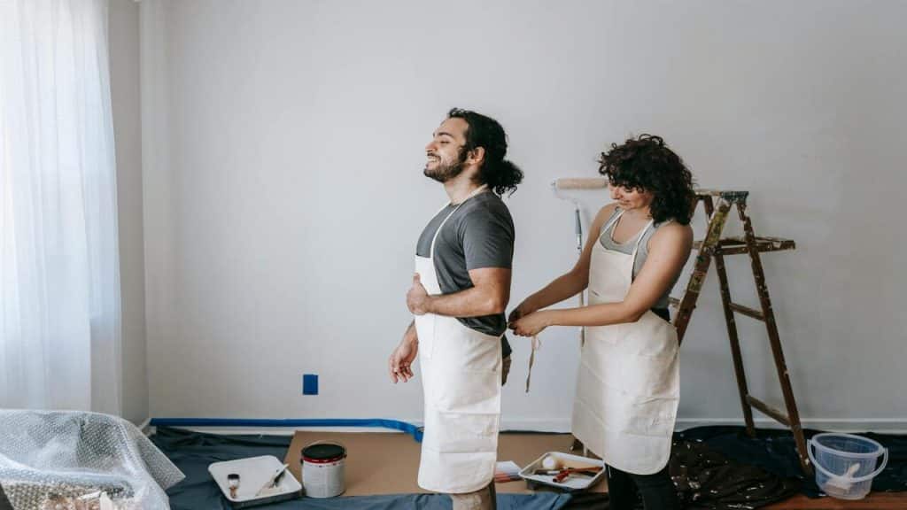 A woman helping her husband put on an apron