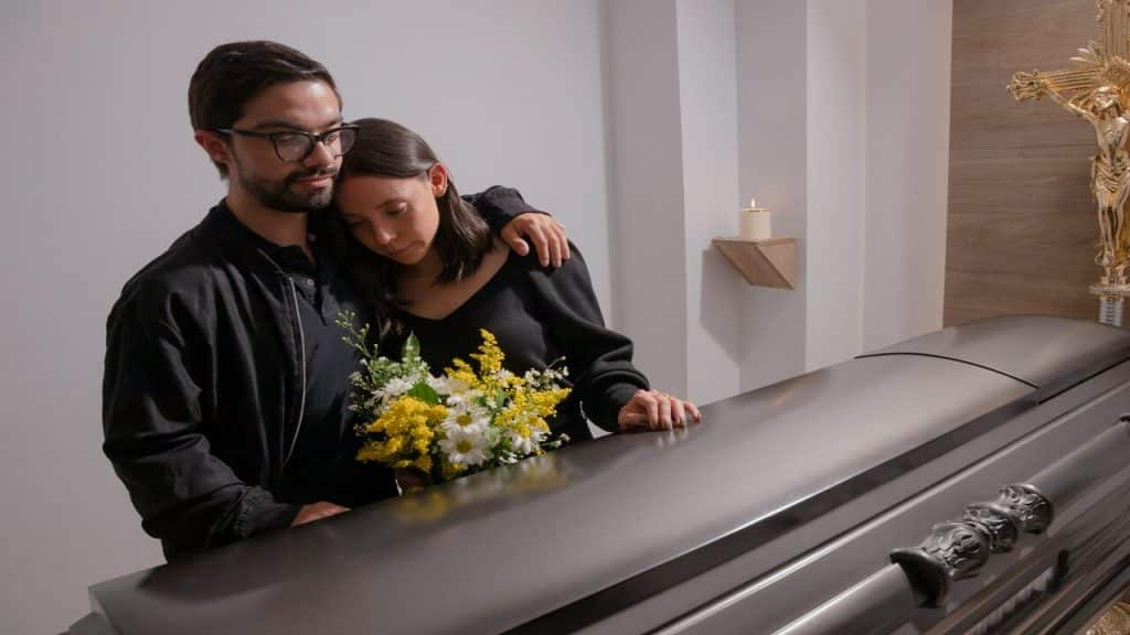 A man comforting his wife at a funeral
