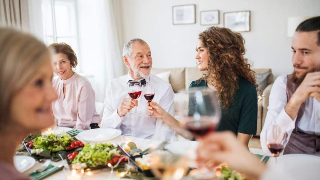 A diverse family enjoys a holiday dinner, clinking wine glasses across a table.