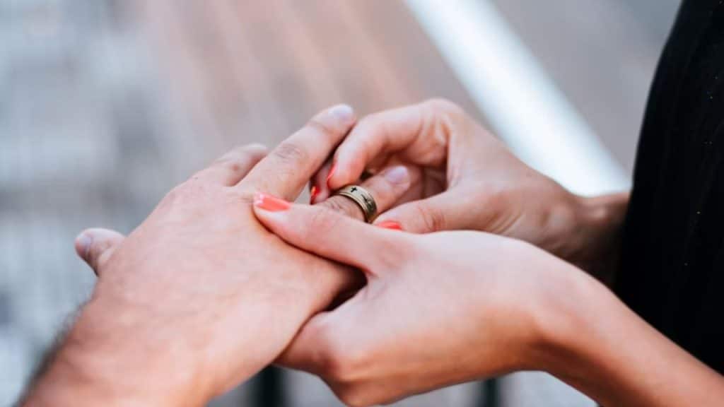 A woman inserting the engagement ring of the man