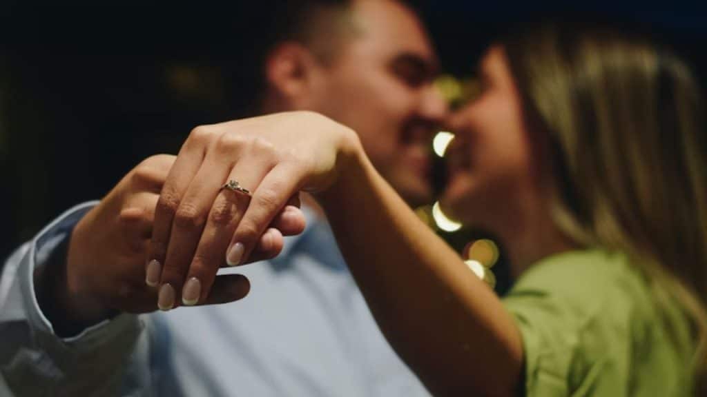 A man and woman embracing after a joyful proposal moment.