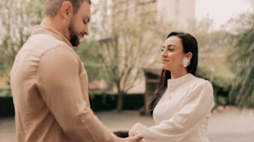 A man looking touched while his partner places a ring on his finger