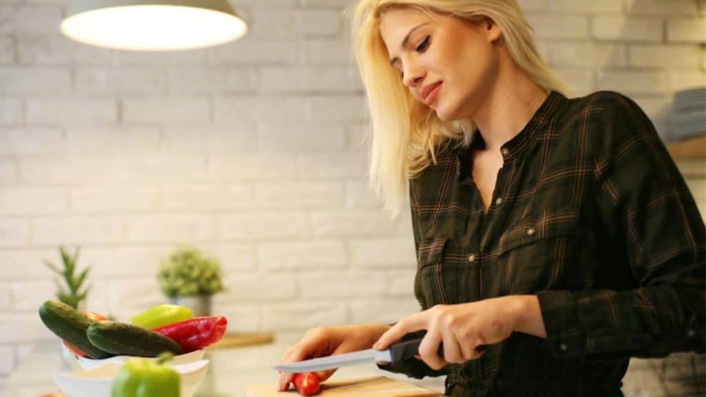 A woman preparing a colorful salad in a kitchen